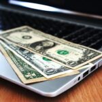 Close-up of US dollar bills placed on a laptop symbolizing digital finance and economy.