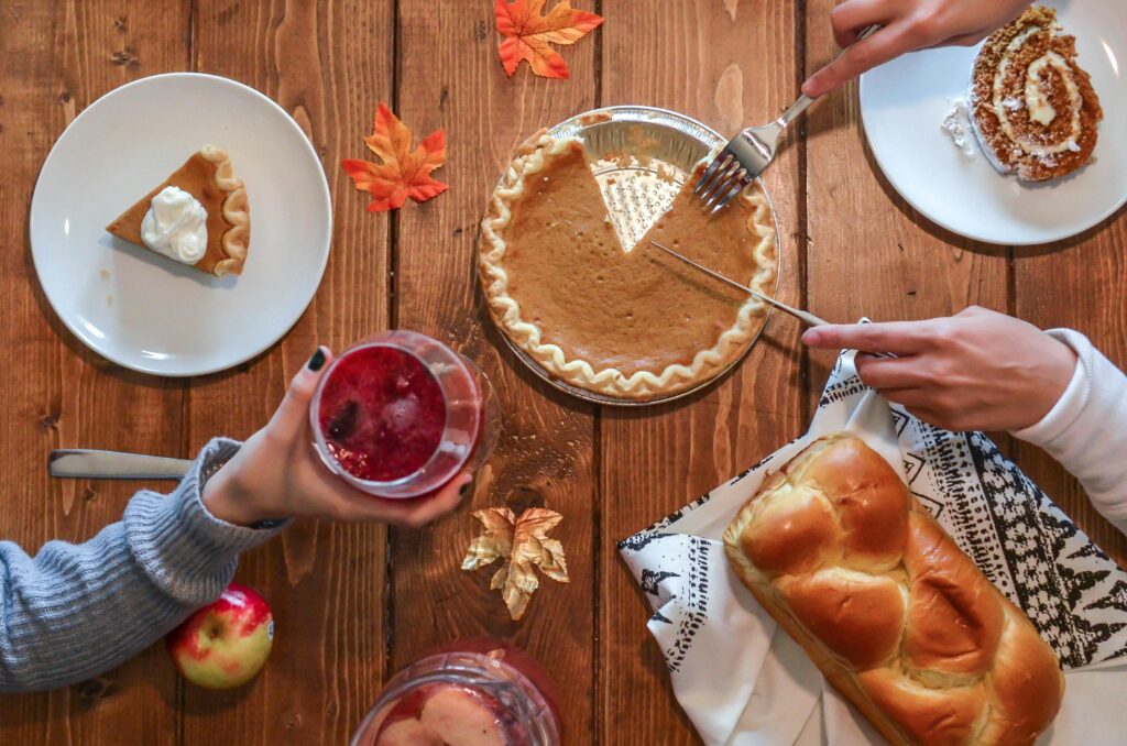 Cozy autumn table setting with pumpkin pie, bread, and drinks. Perfect for Thanksgiving vibes.